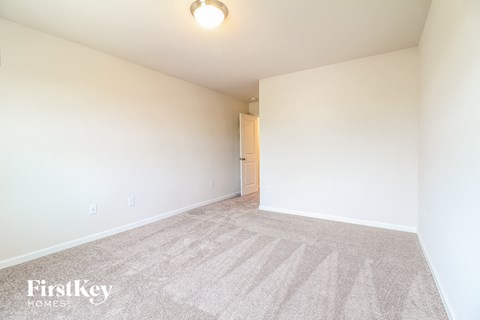 a spacious living room with carpet and white walls