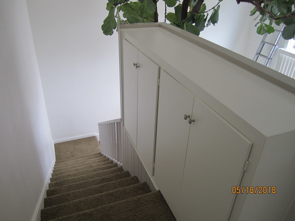 A staircase with a white wall and a plant on top.