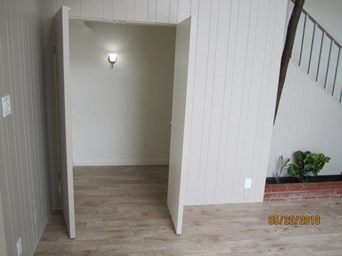 A room with a wooden floor and a wall with vertical panels.