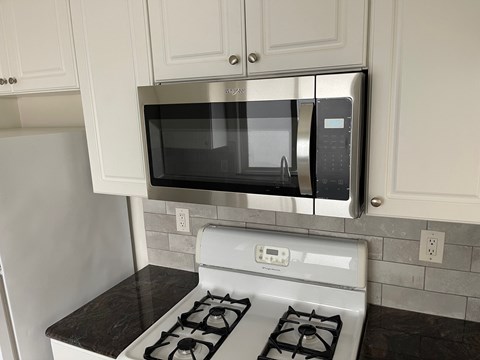 A kitchen with a stove and a microwave above it.