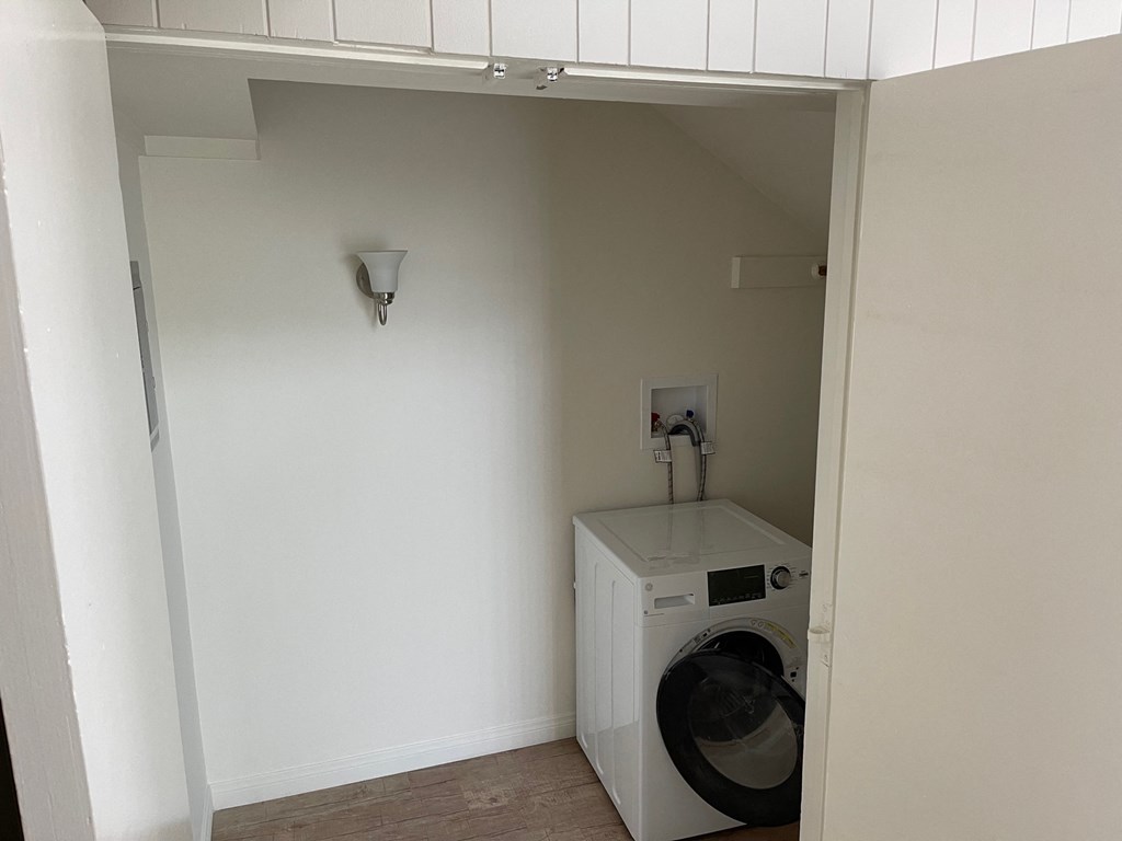 A washing machine is sitting in a small alcove.
