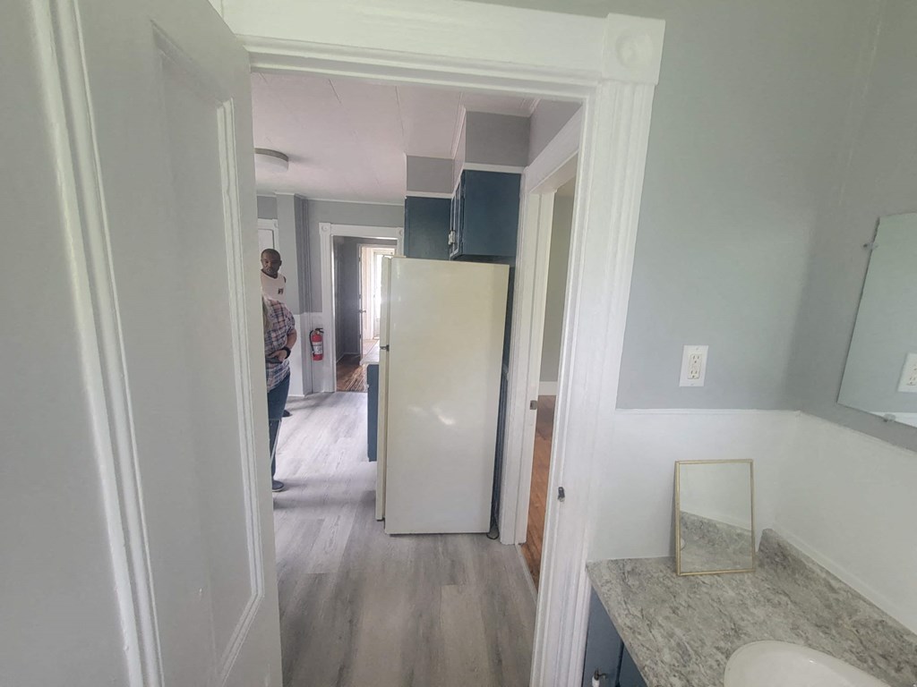 a small kitchen with a white refrigerator and a door to a hallway
