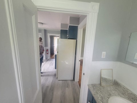 a small kitchen with a white refrigerator and a door to a hallway