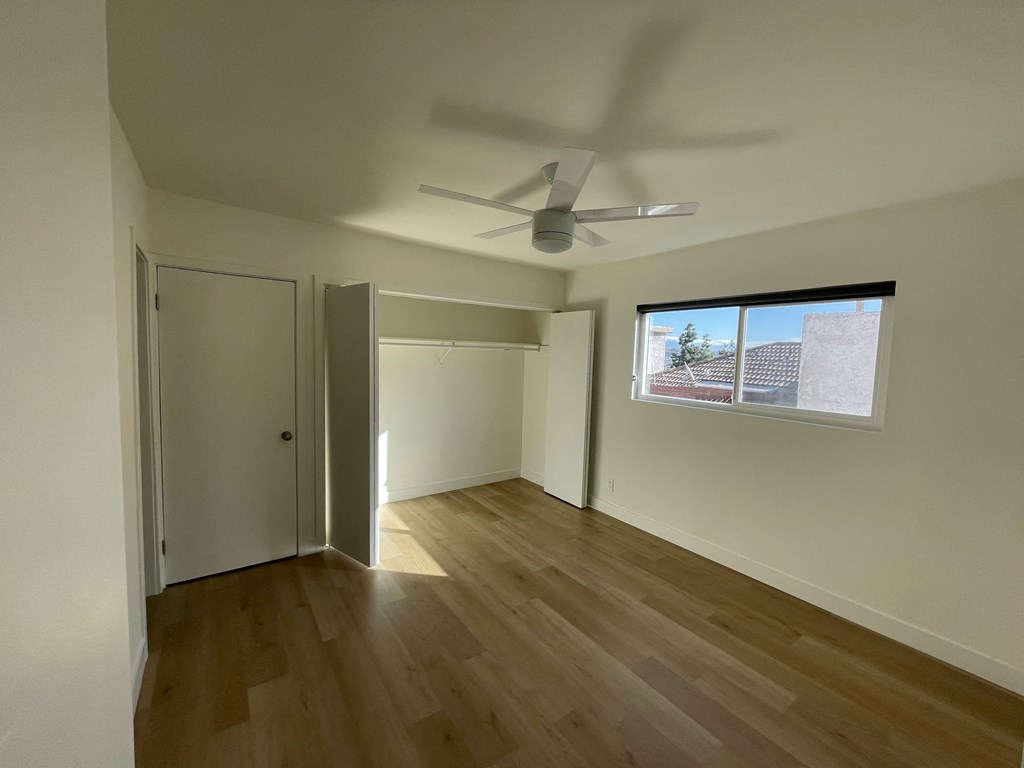 an empty living room with wooden floors and a ceiling fan