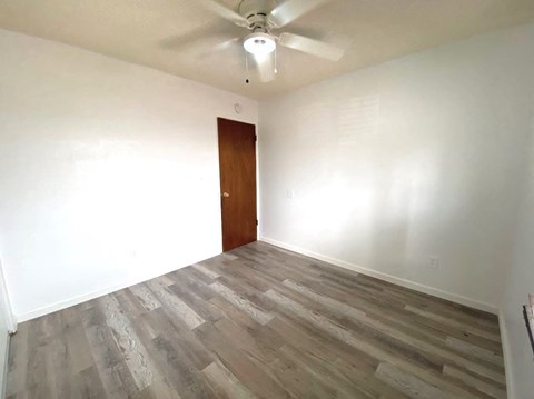 an empty room with wood flooring and a ceiling fan