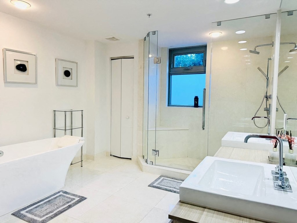 a white bathroom with a tub and a shower and a sink