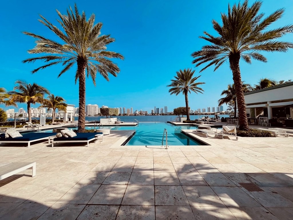a pool with palm trees and a city in the background