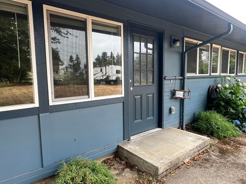 A blue house with a black door and a mailbox on the right side.