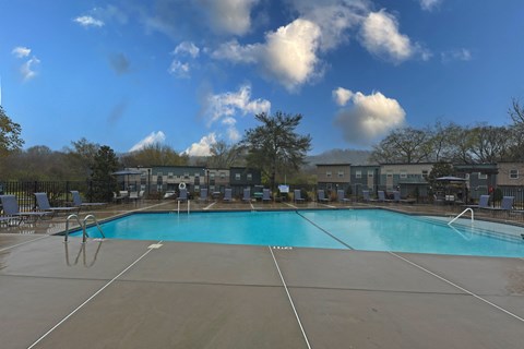 A large outdoor swimming pool with a blue water surface and white lines on the ground.