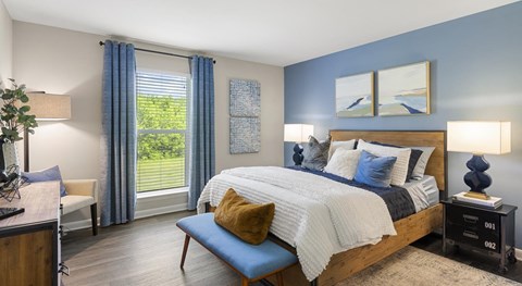 A bedroom with a large bed and a window with blue curtains.