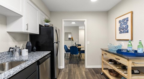 A kitchen with black appliances and a dining table with chairs in the background.