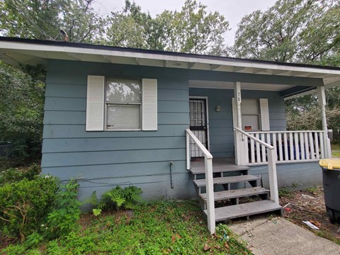 the front of a blue house with a porch and stairs