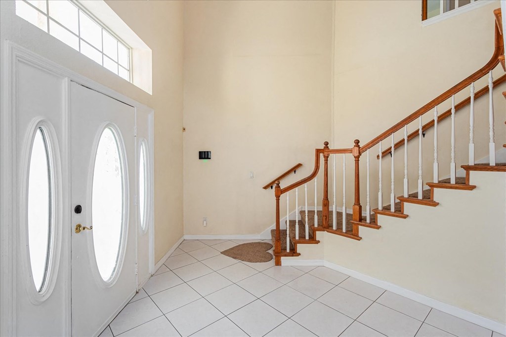 A white door with a round window is on the left of a staircase.