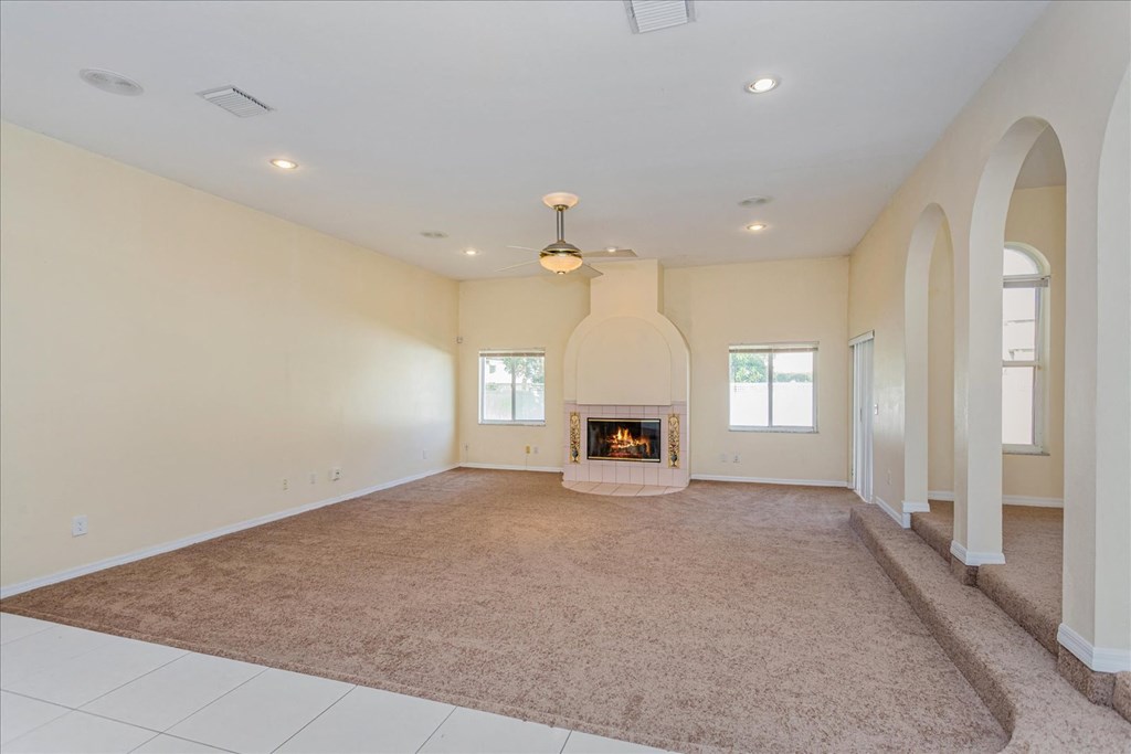 A large, empty room with a fireplace and carpeted floor.