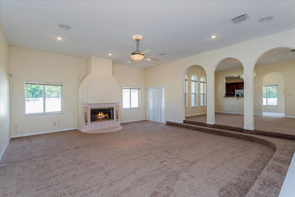 A large, empty room with a fireplace and a carpeted floor.