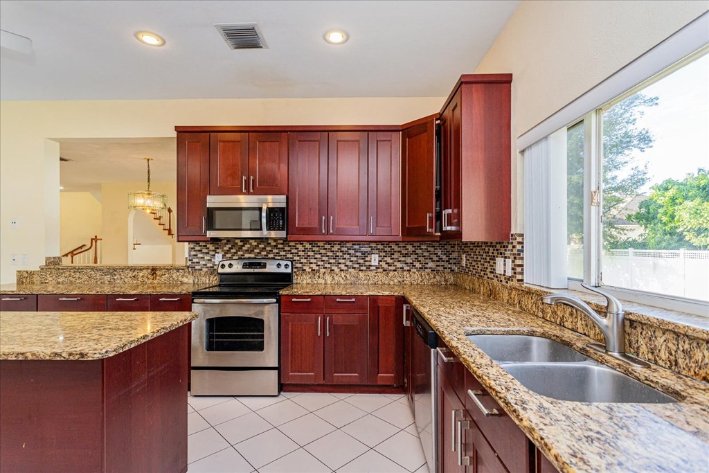 A kitchen with brown cabinets and a stone backsplash.