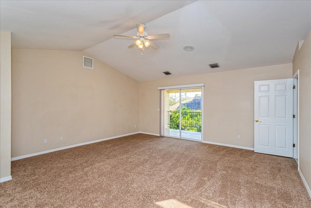 A room with a carpeted floor and a ceiling fan.
