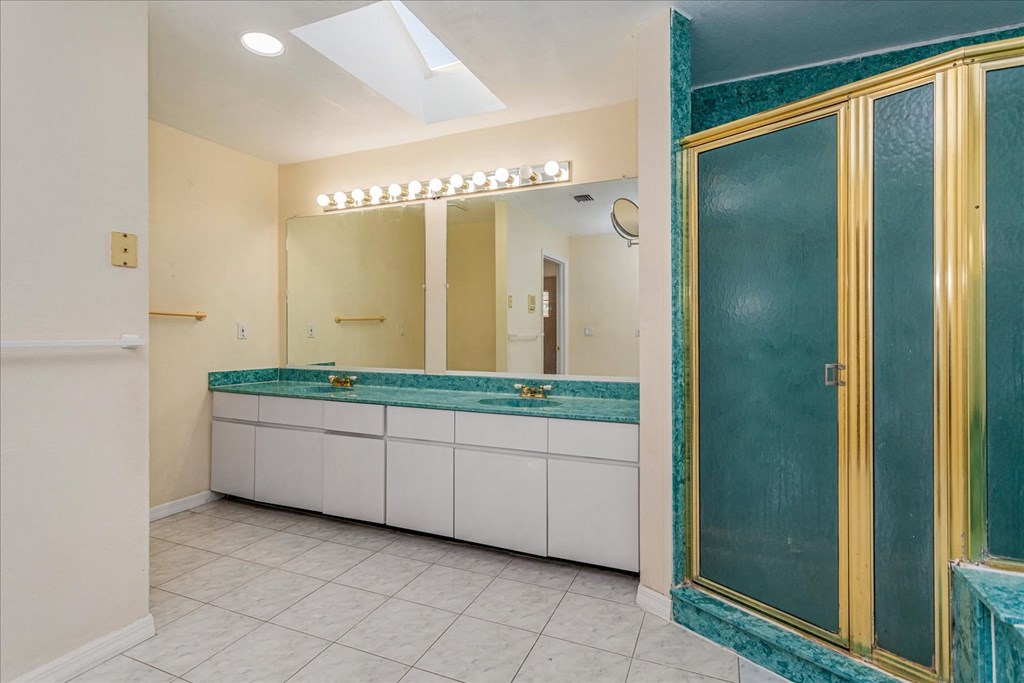 A bathroom with a green marble counter top and white cabinets.