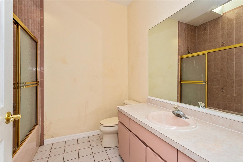 A bathroom with a toilet, sink, and mirror.