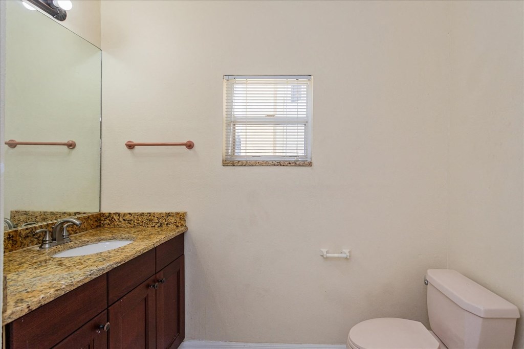 A bathroom with a toilet, sink, and mirror.