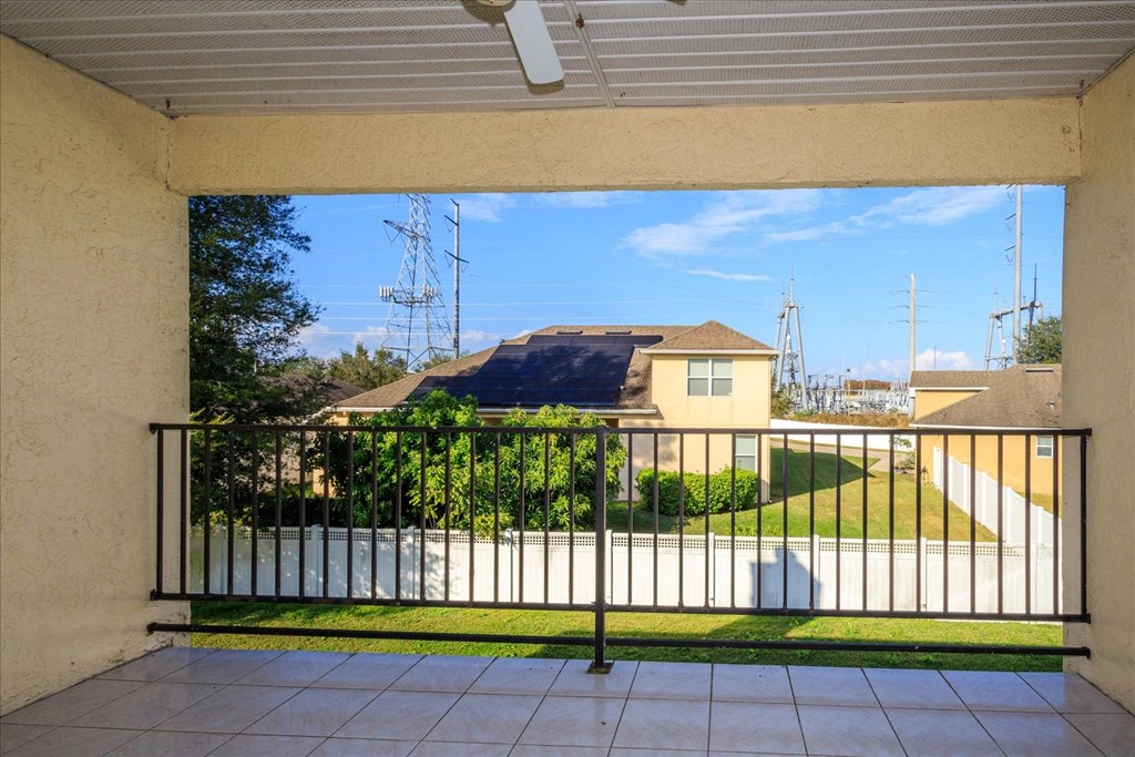 A balcony with a black railing overlooking a green lawn and a house.