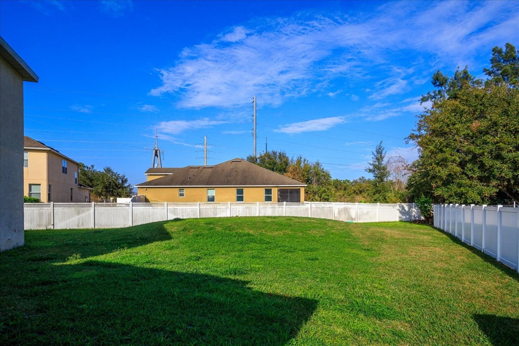 A grassy field with a white fence and a building in the background.