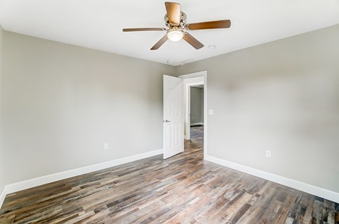 an empty living room with wood floors and a ceiling fan