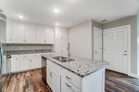 a kitchen with white cabinets and granite counter tops