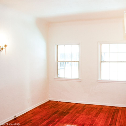 a empty room with two windows and a wooden floor