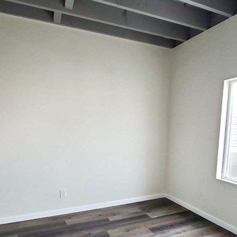 A room with a window and wooden flooring.