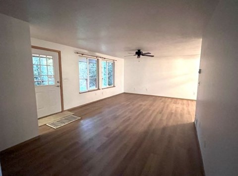 an empty living room with a ceiling fan