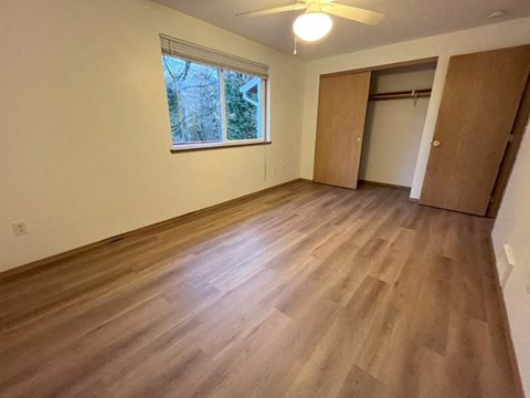 an empty living room with wooden floors and a window