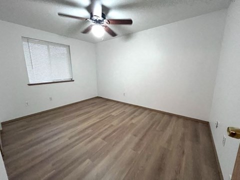 an empty room with a ceiling fan and wood floors