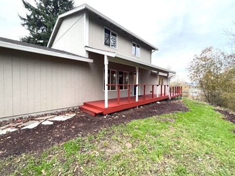 a white house with a red porch in the grass