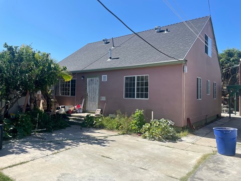 a pink house with a gray roof and a driveway