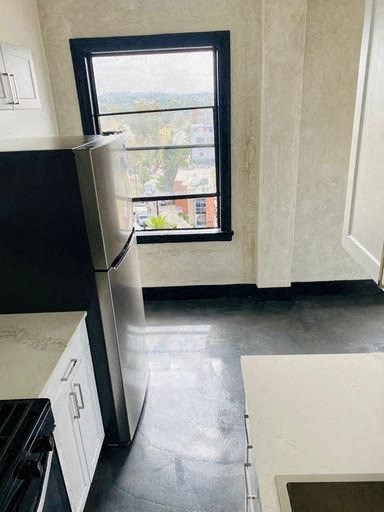A black refrigerator in a kitchen with a window.