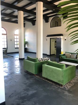 a lobby with green couches and chairs and a palm tree