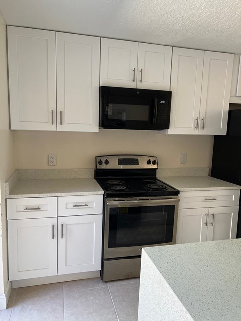 a kitchen with white cabinets and a stove and a microwave