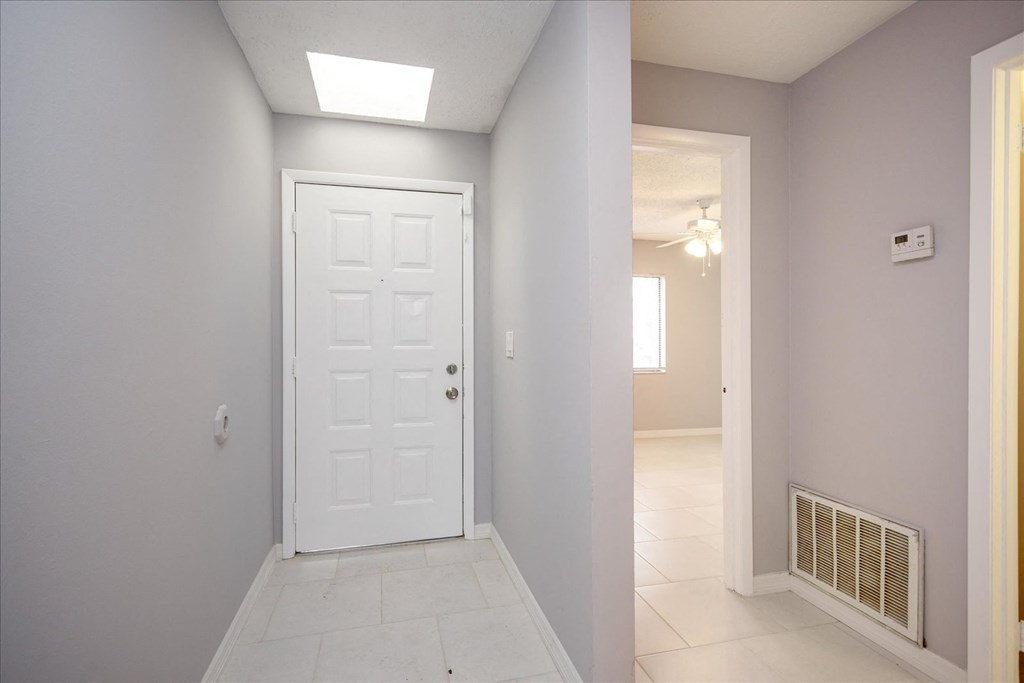 A white door is in a hallway with a light on the ceiling.