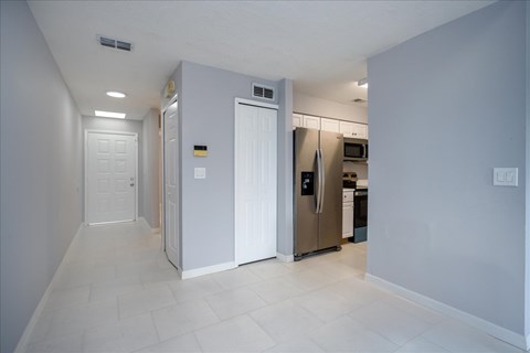 A kitchen with white cabinets and appliances in a white room.