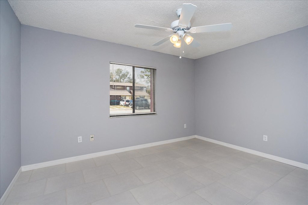 Empty room with a ceiling fan and a window.
