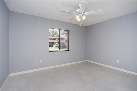 A room with a ceiling fan and a window.