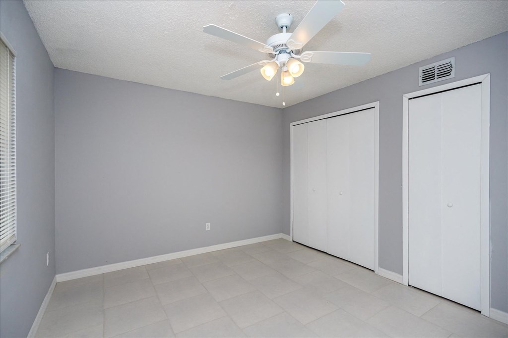 A room with a ceiling fan and two doors.