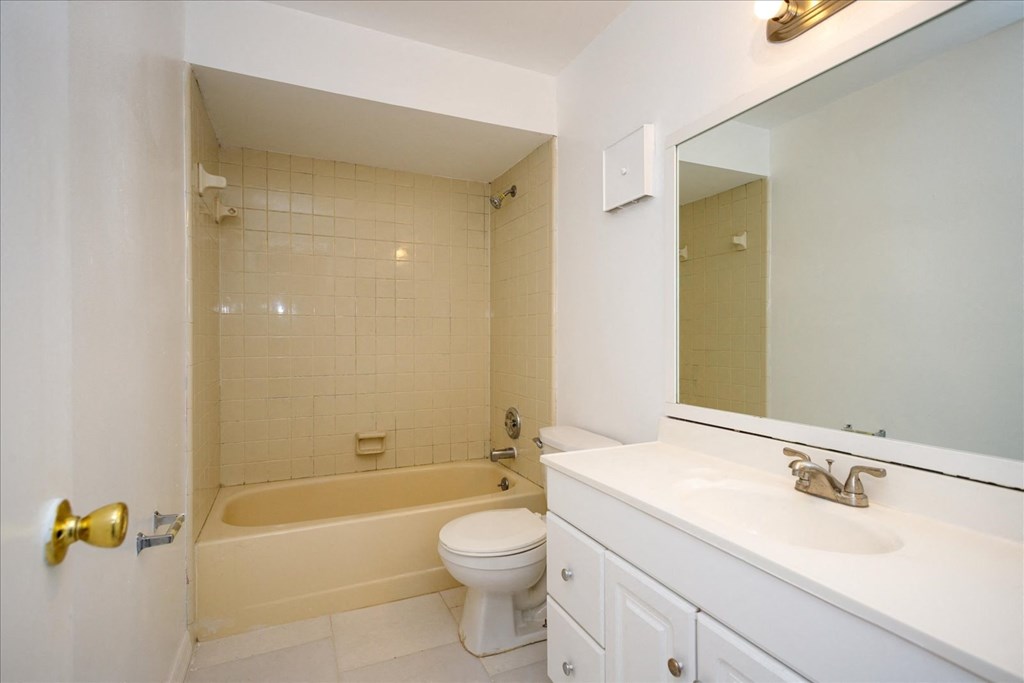 A white bathroom with a beige tub, toilet, and sink.