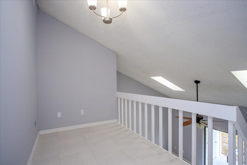 A room with a chandelier and a staircase.
