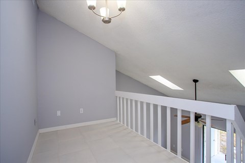 A room with a chandelier and a staircase.