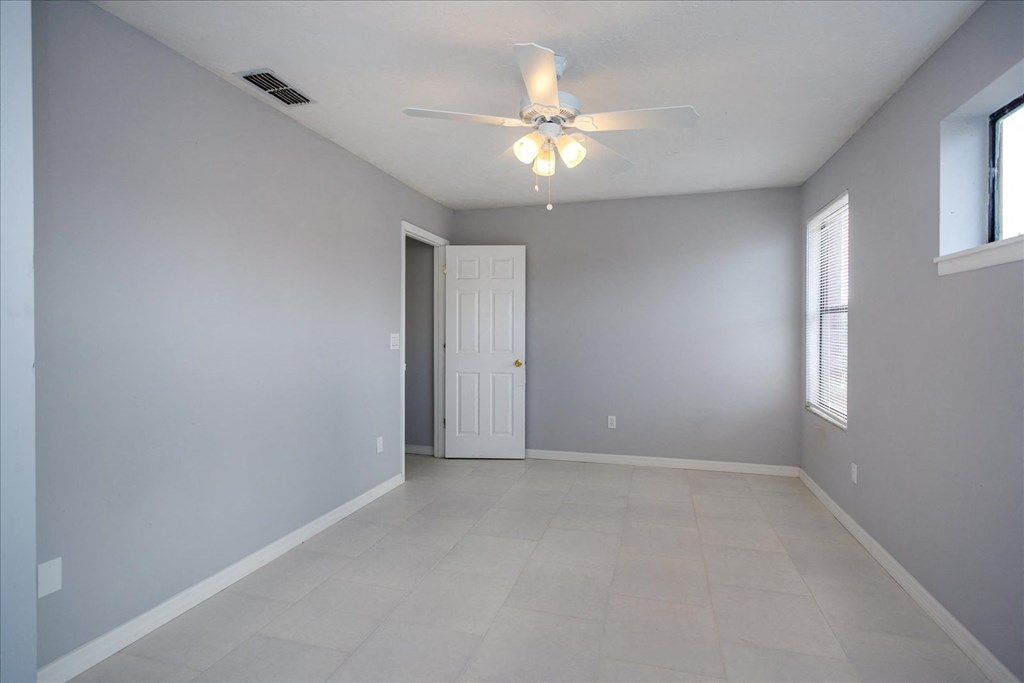 A room with a ceiling fan and a door.