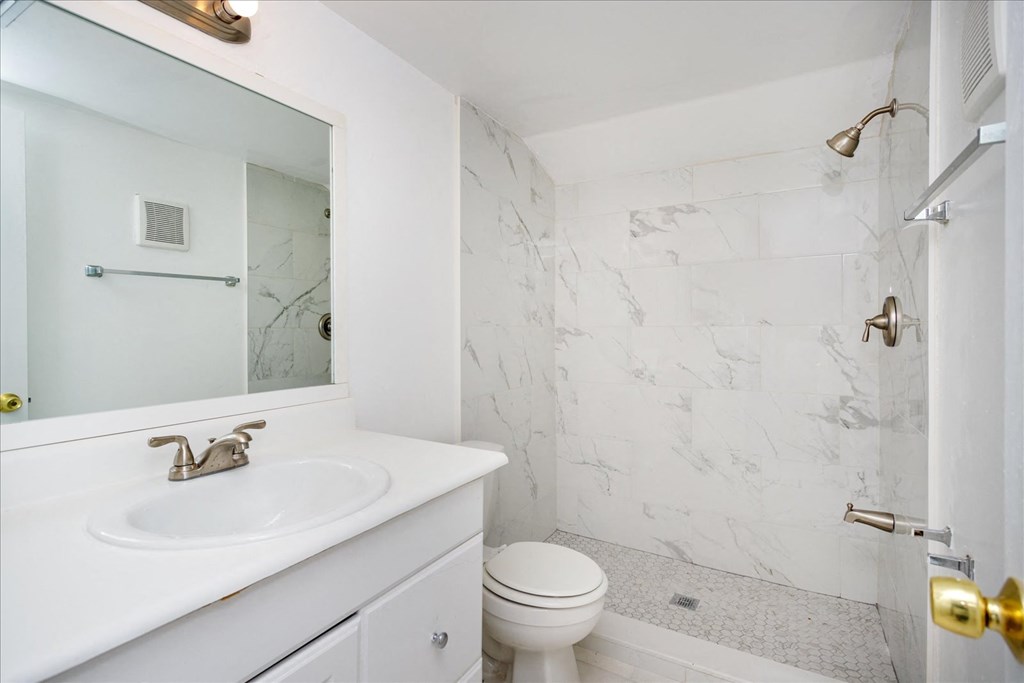 A white bathroom with a marble wallpaper.