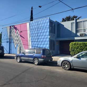 a mural on the side of a building with cars parked in front