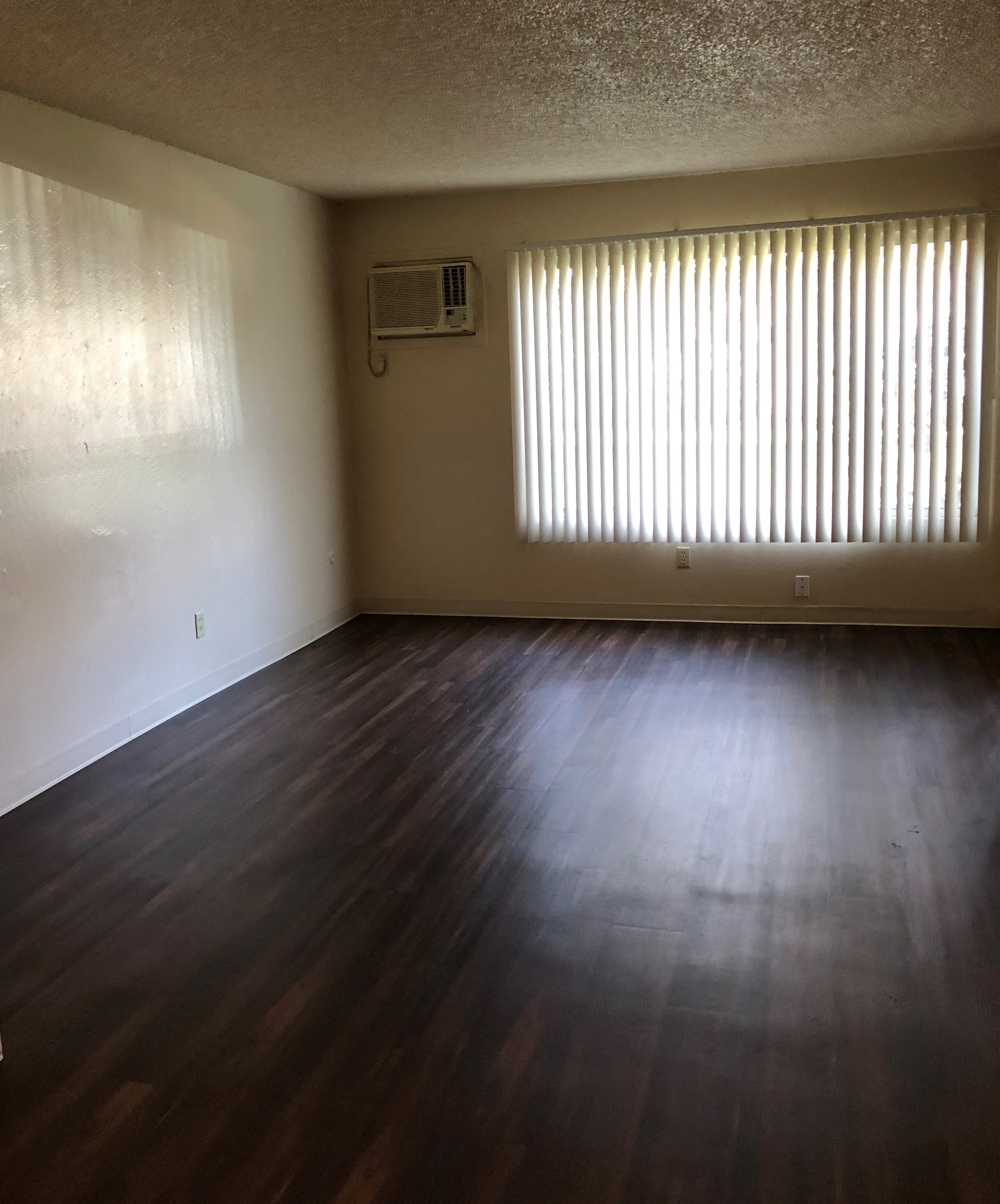 A room with wooden floors and a window with blinds.